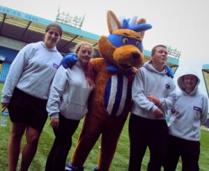 young people on football pitch with mascot